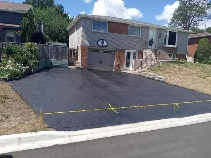 Fresh sealed driveway in front of a house with yellow caution tape.