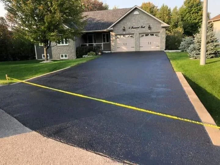 Fresh sealed driveway with yellow caution tape across the surface.