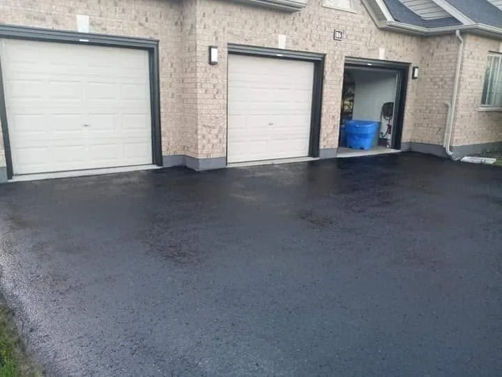 Fresh black sealed driveway surface near garage doors.